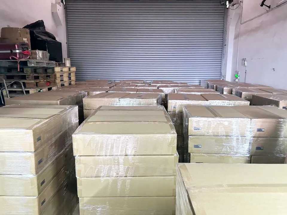 Rows of stretch-wrapped cartons on pallets filling a warehouse in front of a closed roller door.